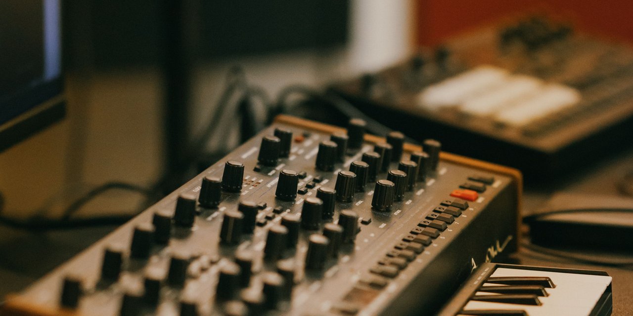 Close-up synthesizer analog dan mixer knob di studio produksi musik elektronik